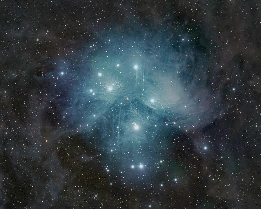 The Pleiades star cluster surrounded by delicate blue reflection nebulosity.